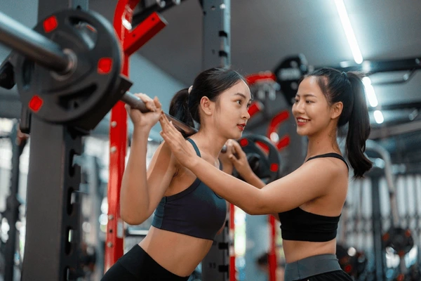 Coach helping athlete with barbell squat